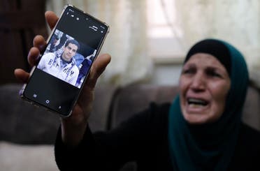 The mother of Iyad Khayri, a Palestinian with special needs, who was shot dead by Israeli police, cries as she shows his picture on her cellphone, at her home in annexed east Jerusalem, on May 30, 2020. (AFP)