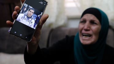 The mother of Iyad Khayri, a Palestinian with special needs, who was shot dead by Israeli police, cries as she shows his picture on her cellphone, at her home in annexed east Jerusalem, on May 30, 2020. (AFP)