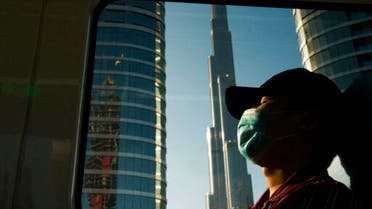 A commuter wearing a face mask to help curb the spread of the coronavirus, sleeps aboard the driverless Metro as it passes the Burj Khalifa in Dubai, United Arab Emirates, Sunday, April 26, 2020. (AP)