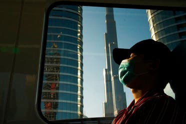 A commuter wearing a face mask as the metro passes the Burj Khalifa in Dubai. (AP)