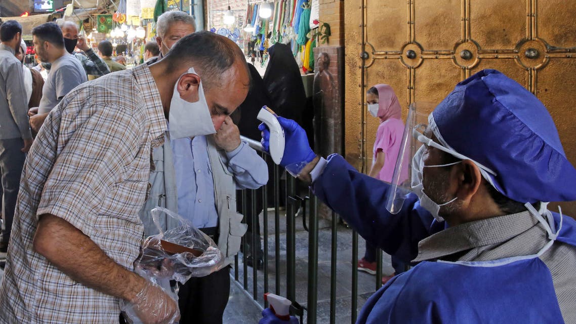 An Iranian official checks the temperature of visitors at the Shah Abdol-Azim shrine in the capital Tehran on May 25, 2020, following the reopening of major Shiite shrines across the Islamic republic, more than two months after they were closed because of the Middle East's deadliest novel coronavirus outbreak.