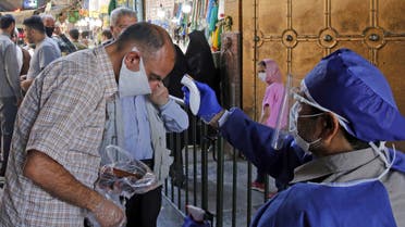 An Iranian official checks the temperature of visitors at the Shah Abdol-Azim shrine in the capital Tehran on May 25, 2020, following the reopening of major Shiite shrines across the Islamic republic, more than two months after they were closed because of the Middle East's deadliest novel coronavirus outbreak. 