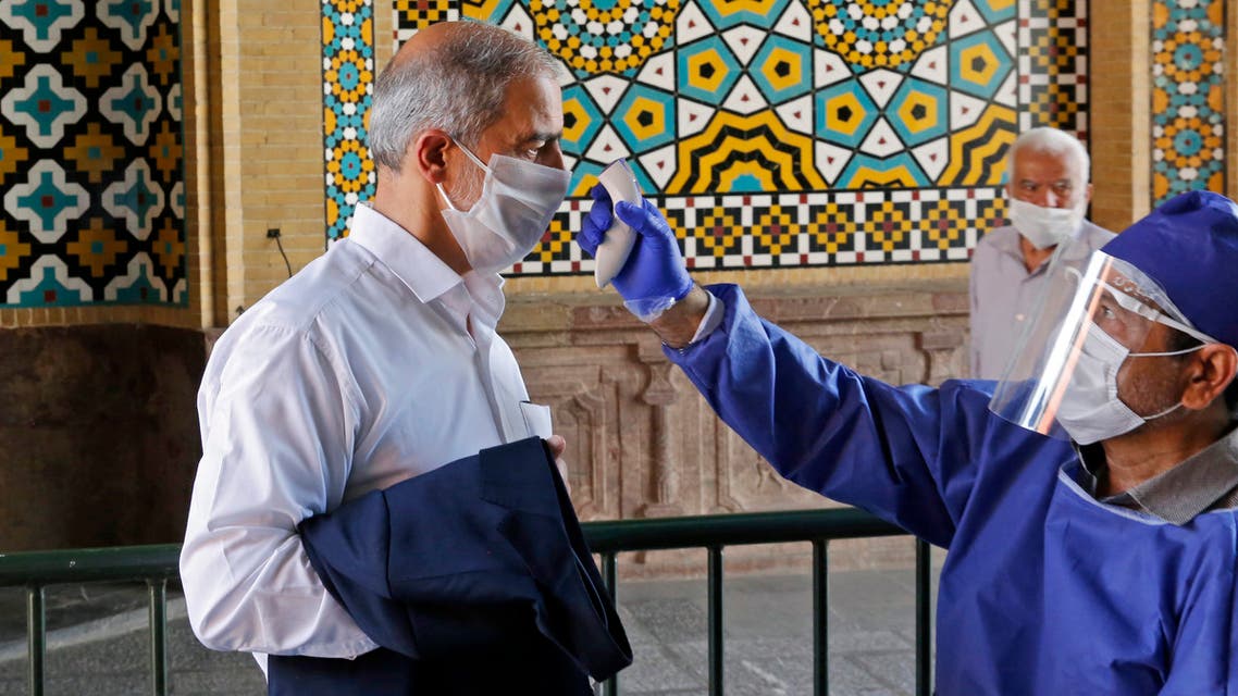 An Iranian official checks the temperature of visitors at the Shah Abdol-Azim shrine in the capital Tehran on May 25, 2020, following the reopening of major Shiite shrines across the Islamic republic, more than two months after they were closed because of the Middle East's deadliest novel coronavirus outbreak.
