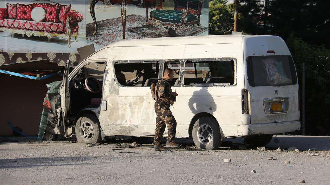 An Afghan security personnel investigates a damaged vehicle carrying employees of Khurshid TV along a roadside, at the site of a bomb blast in Kabul on May 30,2020.