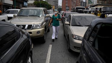 A health worker walks between cars queueing to refuel, near a gas station, in Caracas on May 25, 2020 amid the novel COVID-19 coronavirus outbreak. (AFP)