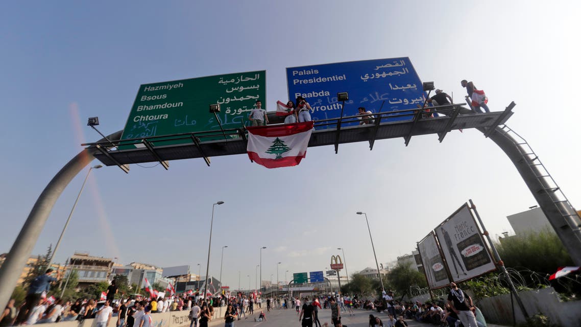Lebanese demonstrators stand on a traffic sign, sprayed with the words Alaa [Abou Fakhr] did not migrate, Alaa died, on the road leading to the Presidential Palace in Baabda, on the eastern outskirts of Beirut on November 13, 2019, nearly a month into an unprecedented anti-graft street movement. Alaa Abou Fakhr died of gunshot wounds overnight after the army opened fire to disperse protesters south of the capital, in the second such death since the start of the largely peaceful protests.