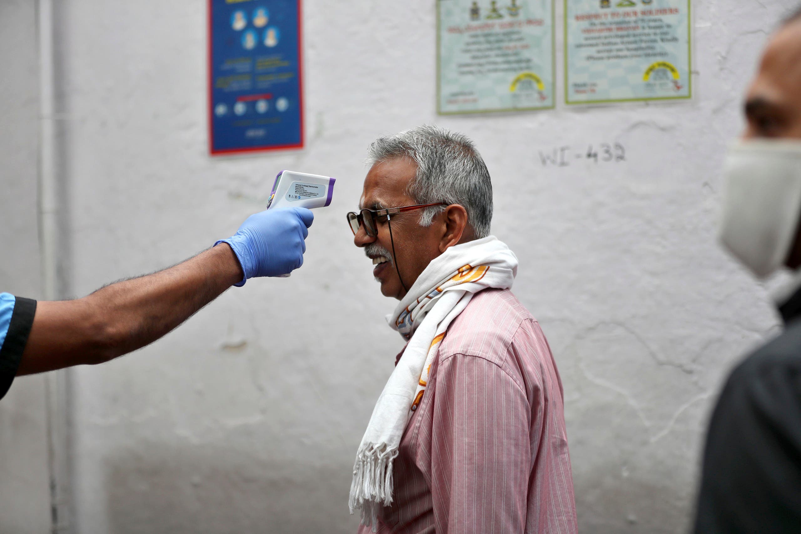 An elderly Indian reacts as a staff member checks his body temperature before allowing him into an eatery in Bengaluru, India on May 30, 2020. (AP)