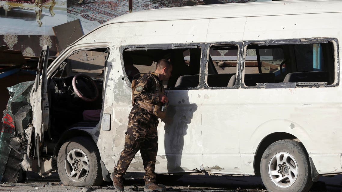 An Afghan security forces member inspects a bus carrying local TV station employees that hit a roadside bomb in Kabul, Afghanistan, Saturday, May 30, 2020. (AP Photo/Rahmat Gul)