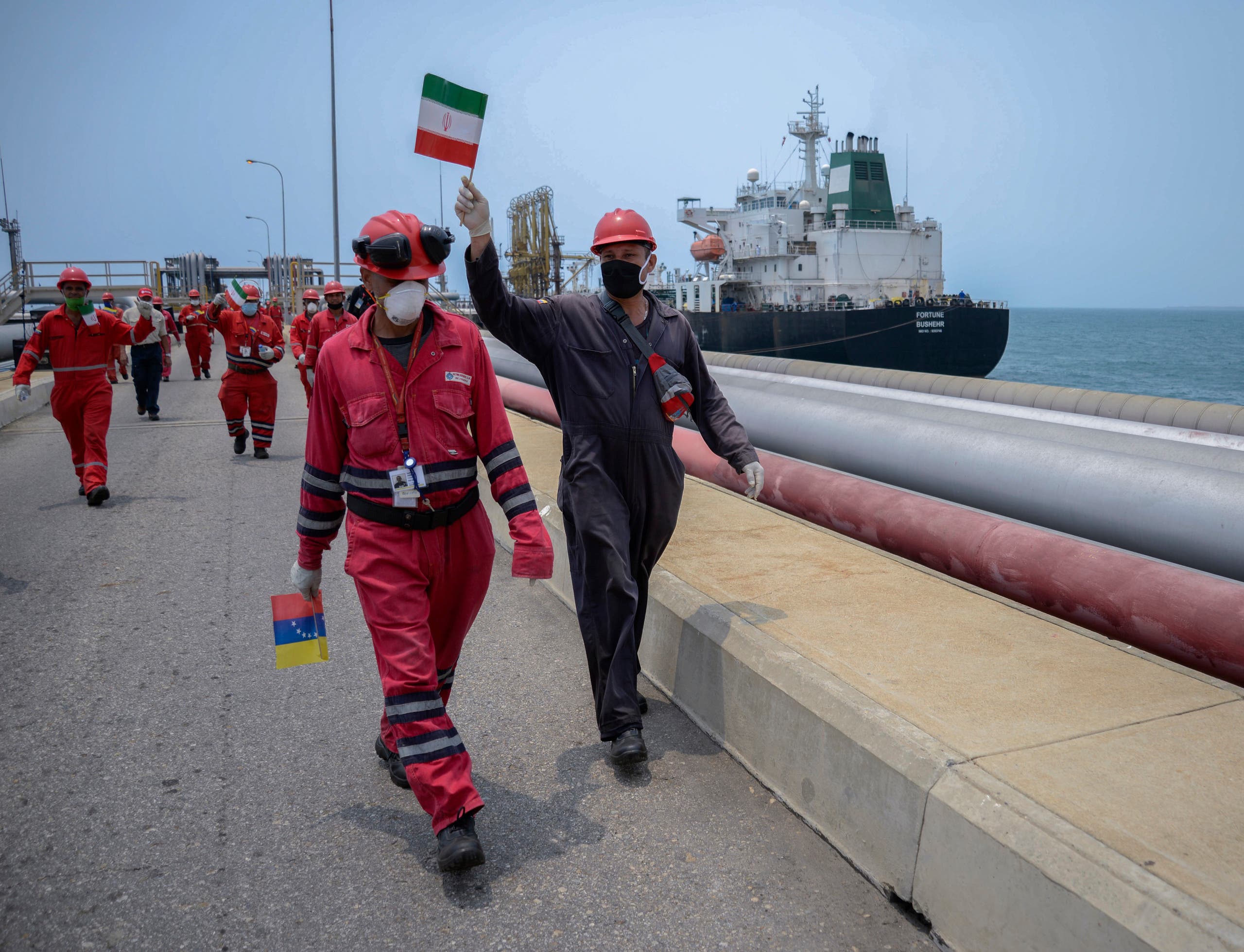 A worker of the Venezuelan state oil company PDVSA waves an Iranian flag as the Iranian-flagged oil tanker Fortune docks in Puerto Cabello, Venezuela, on May 25, 2020. (AFP)