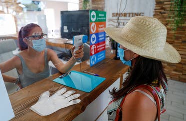 A staff member checks the temperature of a woman before entering, as the swimming pool at the Sporting Club Ostiense reopens with new social distancing and hygiene rules after months of closure due to an outbreak of the coronavirus disease (COVID-19), in Rome, Italy, May 25, 2020. (Reuters)