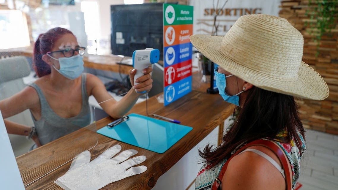 A staff member checks the temperature of a woman before entering, as the swimming pool at the Sporting Club Ostiense reopens with new social distancing and hygiene rules after months of closure due to an outbreak of the coronavirus disease (COVID-19), in Rome, Italy, May 25, 2020. (Reuters)