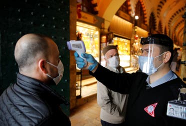 A security guard checks the body temperature of a customer at the entrance of the spice market in Istanbul, Turkey, June 1, 2020. (Reuters) 