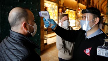 A security guard wearing a protective face mask and a visor checks the body temperature of a customer at the entrance of the spice market, also known as the Egyptian Bazaar, as it reopens after weeks of the close doors amid the spread of the coronavirus disease (COVID-19), in Istanbul, Turkey, June 1, 2020. REUTERS/Umit Bektas