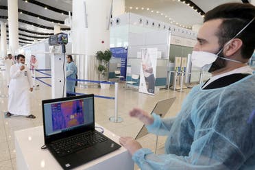 رجل أمن في مطار الرياض الدولي يراقب درجة حرارة المسافرين 