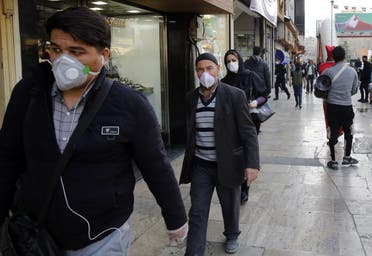 People wearing protective face masks walking along the side of a street by the Tajrish Bazaar in Iran's capital Tehran on March 12, 2020. (AFP)