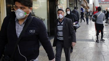 People wearing protective face masks walking along the side of a street by the Tajrish Bazaar in Iran's capital Tehran on March 12, 2020. (AFP)
