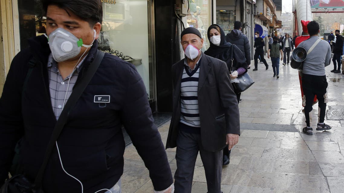 People wearing protective face masks walking along the side of a street by the Tajrish Bazaar in Iran's capital Tehran on March 12, 2020. (AFP)