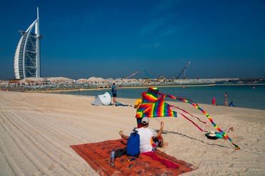 A young boy prepares to fly a kite on a public beach with the Burj al-Arab hotel behind him in Dubai, United Arab Emirates on May 29, 2020. (AP)