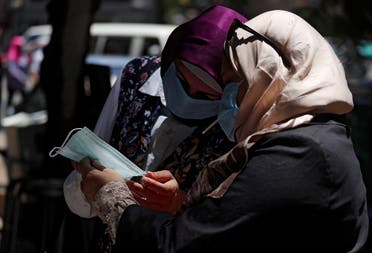 Women wearing face masks check a mask in front of a medical supplies shop in downtown Cairo, after Egypt’s government made masks mandatory in public places and on public transport, in Cairo, Egypt on May 31, 2020. (Reuters)