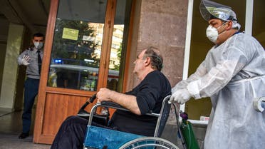 A hospital worker wearing a face mask and protective gear pushes a man in a wheelchair at the Grigor Lusavorich Medical Centre in Yerevan on May 29, 2020, amid the COVID-19 outbreak, caused by the novel coronavirus. Cases of the new coronavirus have overwhelmed Armenia's hospitals, officials said on May 27, raising the prospect that intensive care treatment could be restricted to patients with the best chance of survival. The tiny Caucasus nation of some three million has so far reported 7,774 coronavirus cases and 98 deaths.