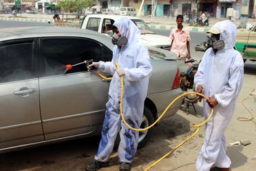 Yemeni sanitation workers, wearing protective gear, spray disinfectant in a neighbourhood in the northern Hajjah province on May 31, 2020, during the ongoing coronavirus pandemic. (AFP)