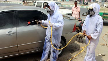 Yemeni sanitation workers, wearing protective gear, spray disinfectant in a neighbourhood in the northern Hajjah province on May 31, 2020, during the ongoing coronavirus pandemic. (AFP)