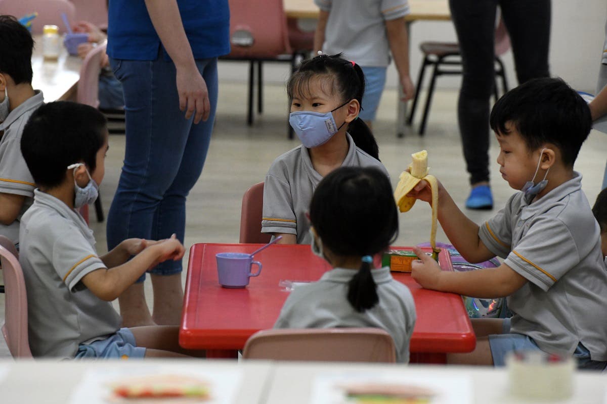 Pre-school children gather around a table inside their classroom as schools reopened in Singapore on June 2, 2020. (AFP)