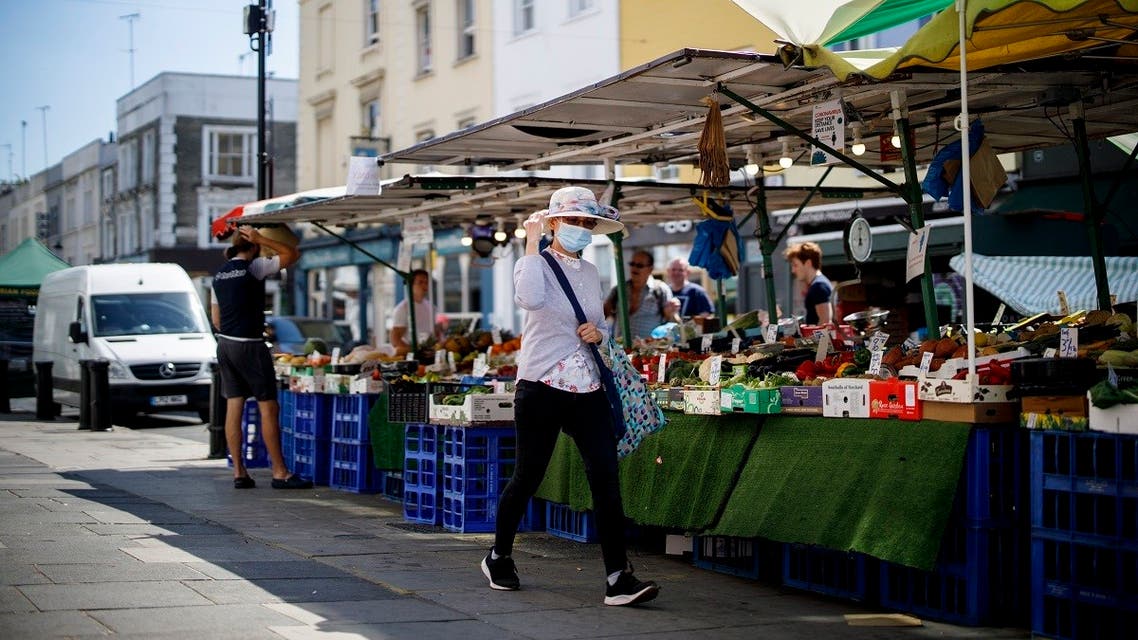 A woman wearing a protective face mask walks past a food stall in Portobello Market in west London on June 1, 2020, following the easing of the lockdown restrictions during the novel coronavirus pandemic. (AFP)