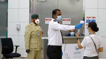 A security man takes temperature of a woman amid the outbreak of the coronavirus disease (COVID-19) at Dubai International Airport, UAE April 27, 2020. (Reuters)