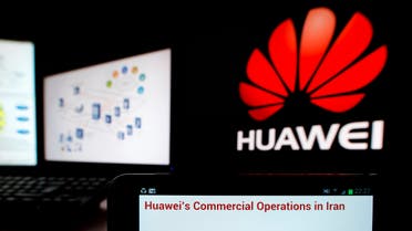 An excerpt of a statement from Chinese telecom equipment firm Huawei is displayed on a smartphone in front of computer screens showing the Huawei logo (R). (Reuters)