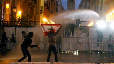 A demonstrator holds up a national flag as police use water cannon during a protest against the newly formed government in Beirut, Lebanon January 22, 2020. (Reuters)