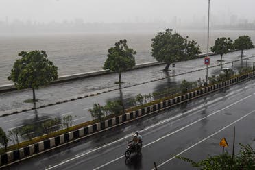 Motorists ride a motorbike on a road near the Marine Drive under heavy rain in Mumbai on June 3, 2020, as cyclone Nisarga barrels towards India’s western coast. (AFP)
