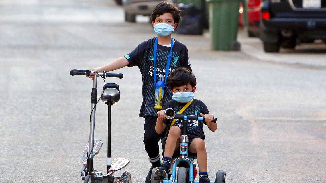 Kuwaiti children, wearing protective facemasks due to the coronavirus pandemic, cycle in a street in the Salwa district of Kuwait City on May 29, 2020.