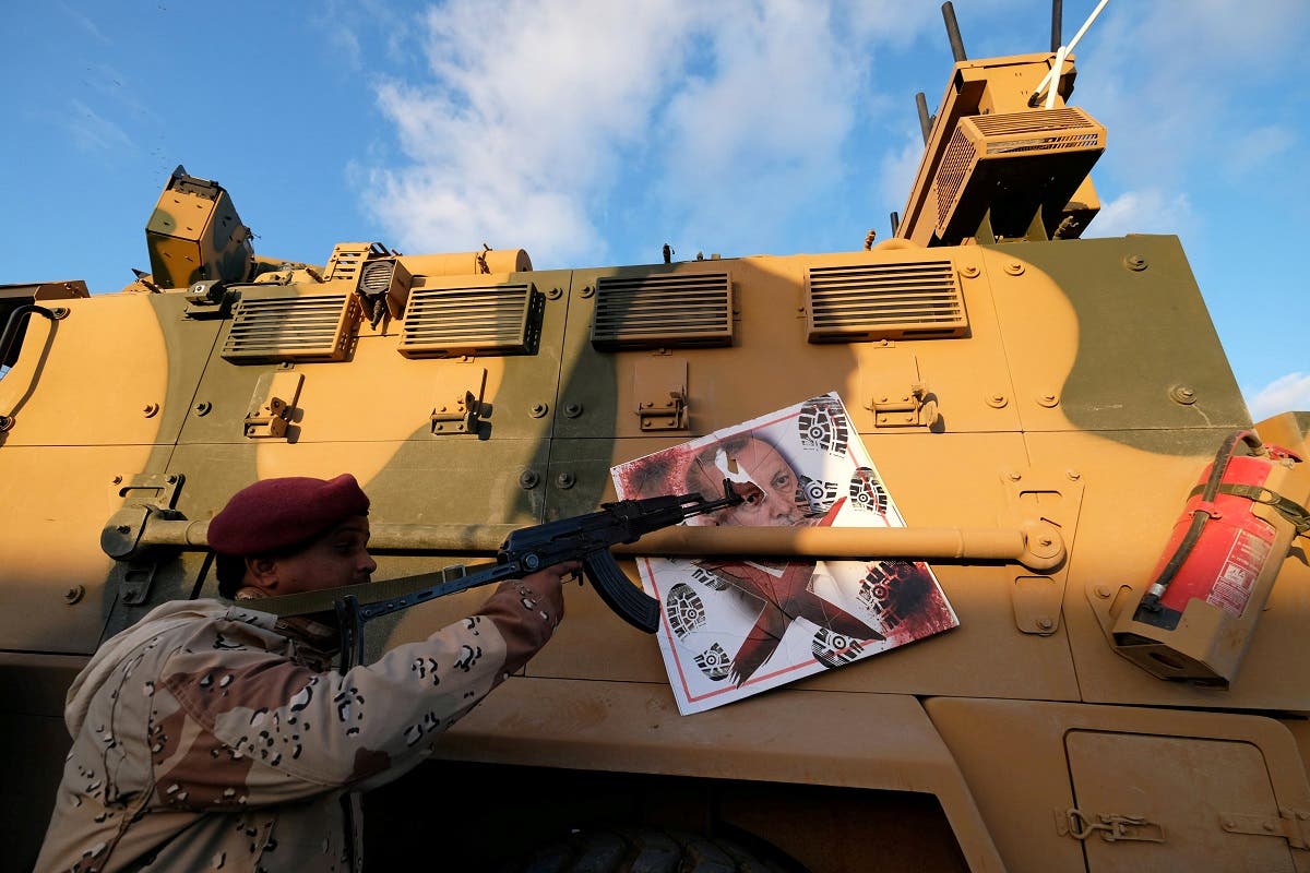 A member of Libyan National Army (LNA) commanded by Khalifa Haftar, points his gun to the image of Turkish President Tayyip Erdogan. (File Photo: Reuters)