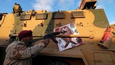 A member of the LNA points his gun to the image of Turkish President Tayyip Erdogan on a Turkish military armored vehicle. (File Photo: Reuters)