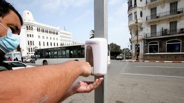A man wearing a protective face mask uses a hand sanitizer dispenser on the street following the spread of the coronavirus disease (COVID-19), in Algiers, Algeria March 21, 2020. (Reuters)