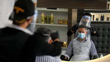 A barber wears a protective face shield and gloves as he cuts hair of a customer at a local barber shop after its reopening, following the outbreak of the coronavirus disease (COVID-19), in Isa Town, Bahrain May 27, 2020. REUTERS/Hamad I Mohammed