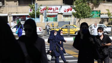 Iranian people wear protective face masks and gloves, following the outbreak of the coronavirus disease (COVID-19), as they walk in Vali-E-Asr street, in Tehran. (Reuters)