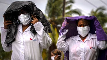 Health professionals who volunteered to travel to Kuwait to treat of coronavirus patients walk in the rain after attending their farewell ceremony in Havana, Cuba, Thursday, June 4, 2020. (AP Photo/Ramon Espinosa)