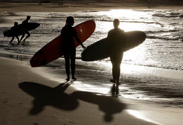 In this April 28, 2020, photo, surfers walk the beach in Sydney, Australia. (AP)