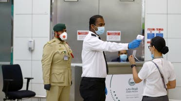 A security man takes temperature of a woman amid the outbreak of the coronavirus disease (COVID-19) at Dubai International Airport. (Reuters)