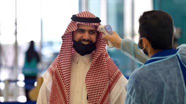A Saudi health worker takes the temperature of a passenger at terminal 5 in the King Fahad International Airport, designated for domestic flights, in the capital Riyadh on May 31, 2020, after authorities lifted the ban on flights within the country. 