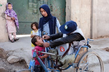 In this photo taken on March 20, 2019, an Afghan health worker administers a polio vaccine to a child as people look on in Kandahar province's Arghandab district. (AFP)