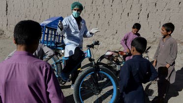 In this photo taken on May 19, 2020, 27-year-old Afghan cyclist Idrees Syawash (C) talks to children during an awareness campaign on coronavirus in the Surkh Rod district of Nangarhar province. (AFP)
