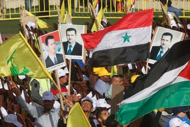 Supporters of Lebanon's Hezbollah leader Sayyed Hassan Nasrallah carry flags and pictures of Syria's President Bashar al-Assad during a rally marking al-Quds Day, (Jerusalem Day) in Maroun Al-Ras village, near the border with Israel, southern Lebanon June 8, 2018. (Reuters)