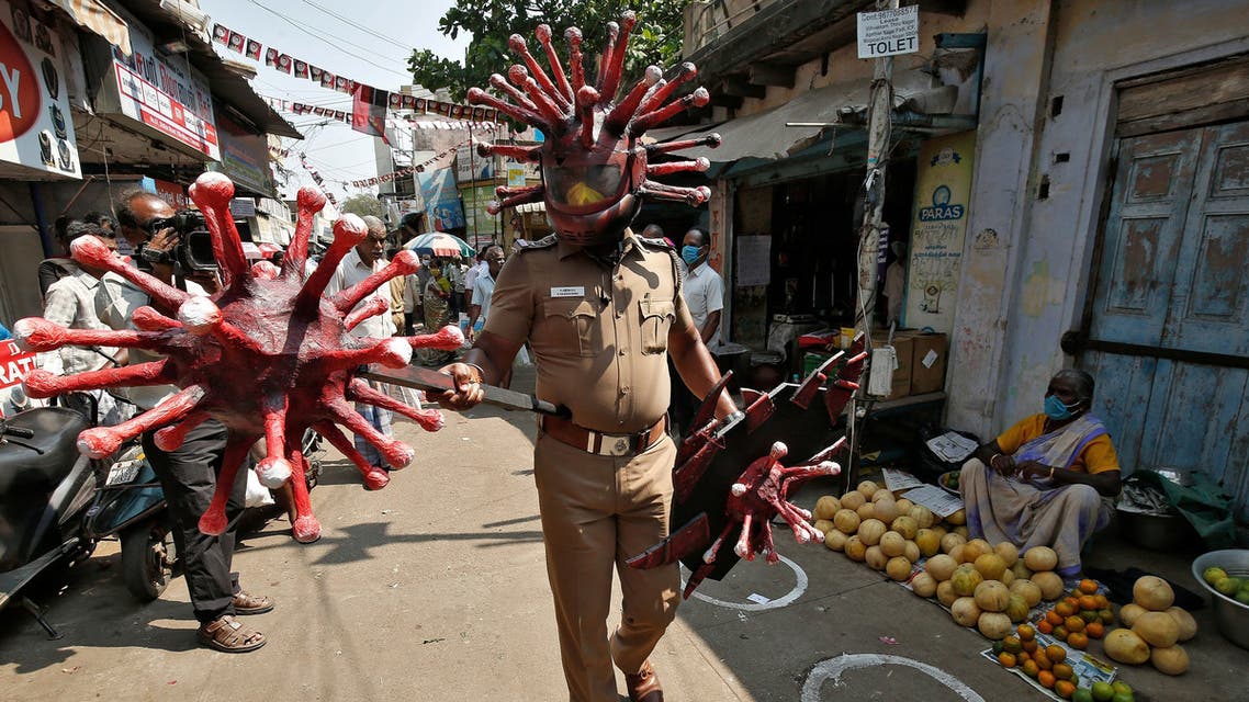 A police officer wearing a helmet and holding shields depicting coronavirus walks in a market area to advice people to maintain safe distance during a 21-day nationwide lockdown to slow the spreading of coronavirus disease (COVID-19) in Chennai. (Reuters)
