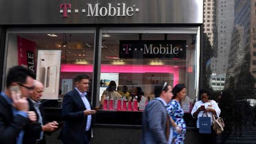 Pedestrians use their smart phones as they pass a T-Mobile retail store in Manhattan, New York, U.S., September 22, 2017. (Reuters)