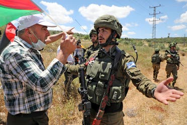Palestinian protesters from the village of Haris in the occupied West Bank argue with Israeli soldiers, on May 29, 2020, during a protest against the expropriation of Palestinian land in favor of the Israeli settlement of Revava. (AFP)
