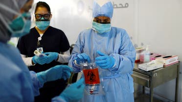 A member of medical staff wearing a protective face mask and gloves carries a swab tested during drive-thru coronavirus disease testing (COVID-19) at a screening centre in Abu Dhabi, United Arab Emirates March 30, 2020. (Reuters)