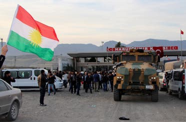 A man waves a Kurdistan flag as a Turkish military truck escorts a convoy of peshmerga vehicles at Habur border gate, which separates Turkey from Iraq, near the town of Silopi in southeastern Turkey, October 29, 2014. (Reuters)